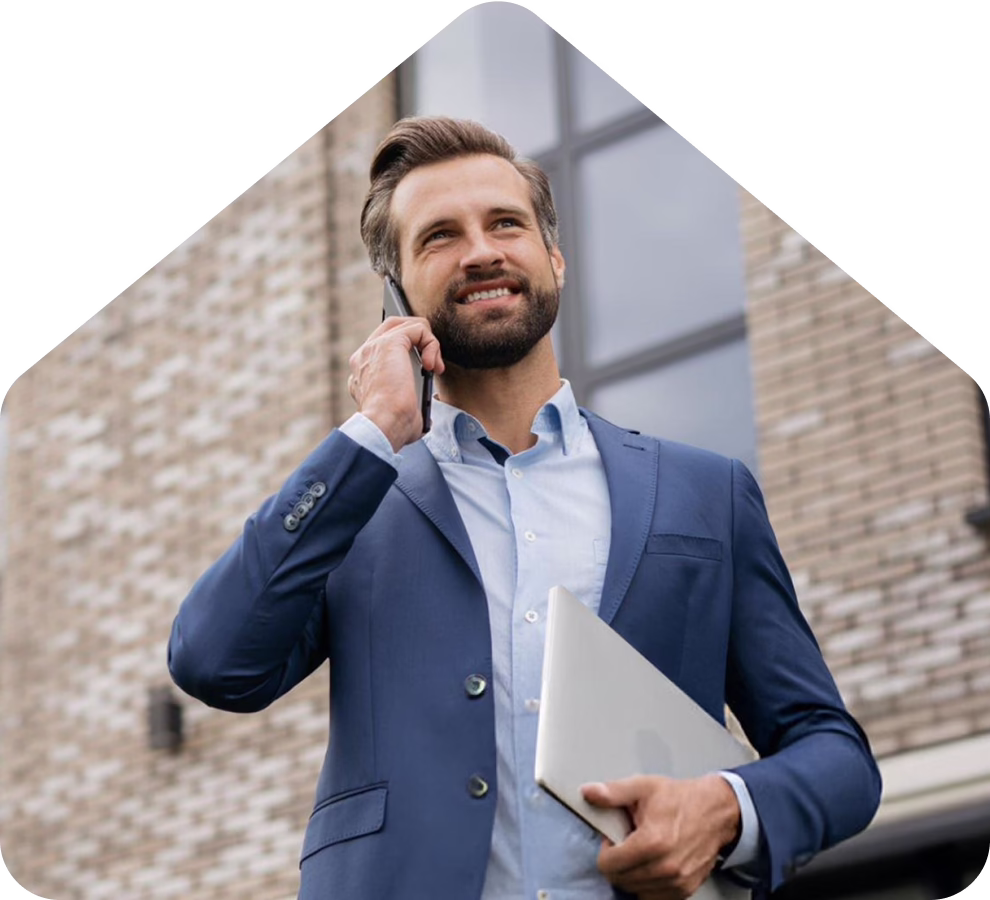A man in a suit is engaged in a phone conversation, looking focused and professional.